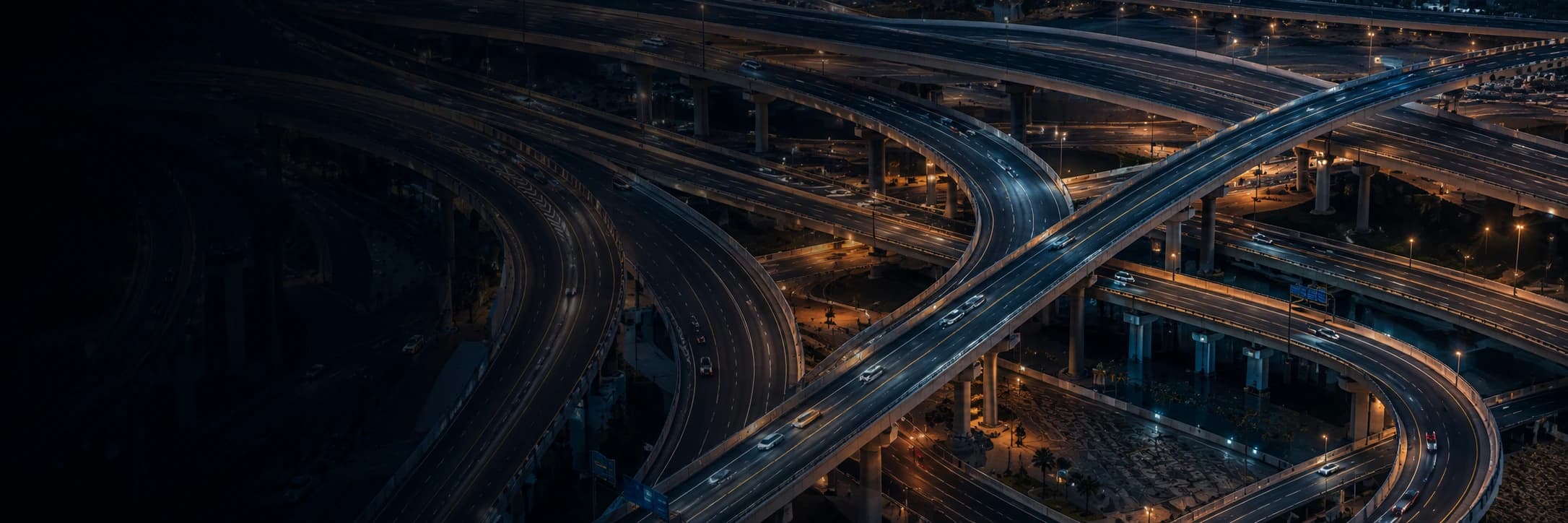 Aerial night view of a Dubai highway interchange, representing SecurePath's real-time GPS-tracked vehicle network
